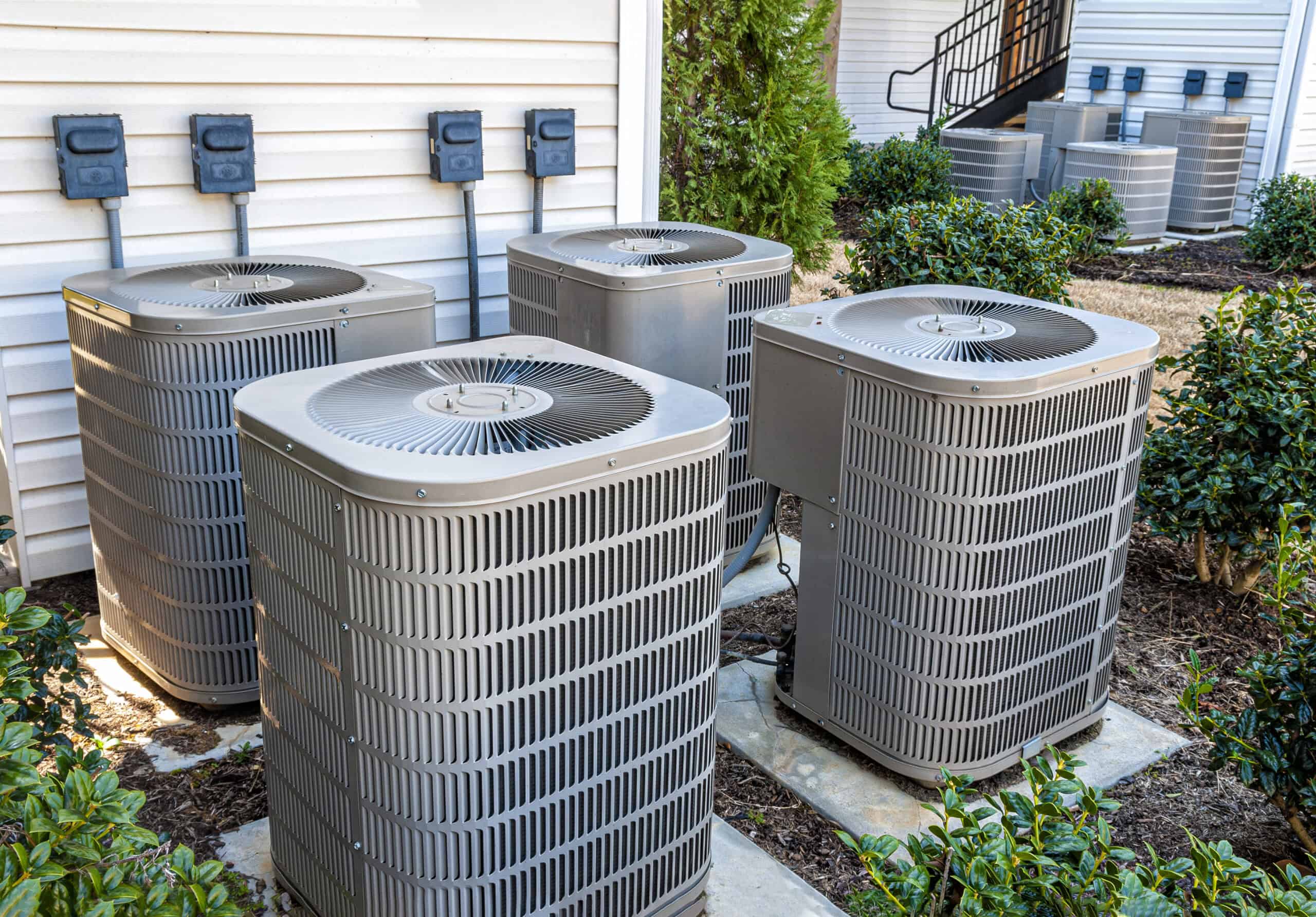 Apartment Air Conditioners REWORKED Horizontal shot of four apartment air conditioners outside.
